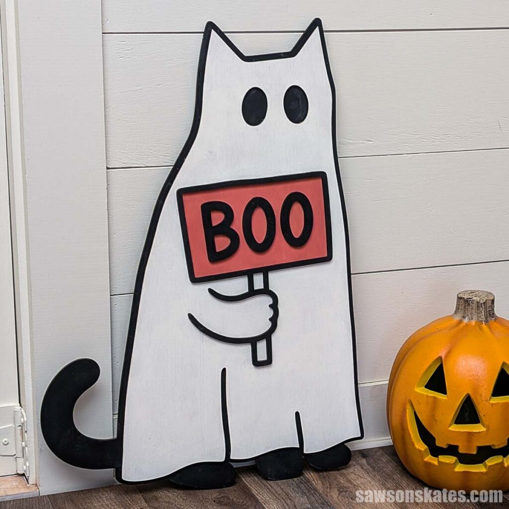 Cat that looks like a ghost holding a sign with the word BOO