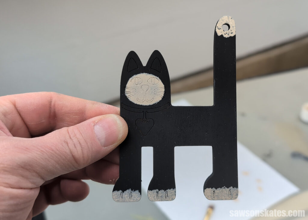 Scott holding a wooden cat with its body painted black and its face, tail and feet painted cream.
