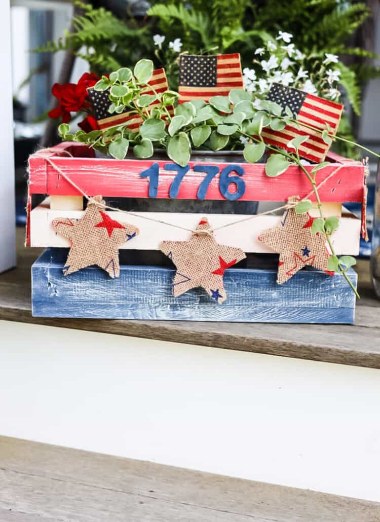 Patriotic planter box centerpiece painted in red, white, and blue with the numbers ‘1776’ on the front.