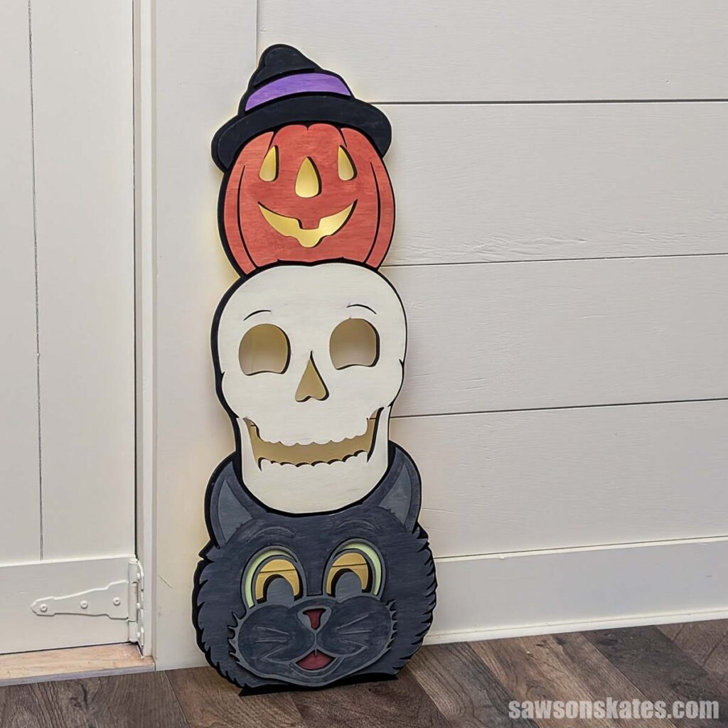 Halloween totem porch leaner with a jack-o-lantern, skull, and cat next to a doorway