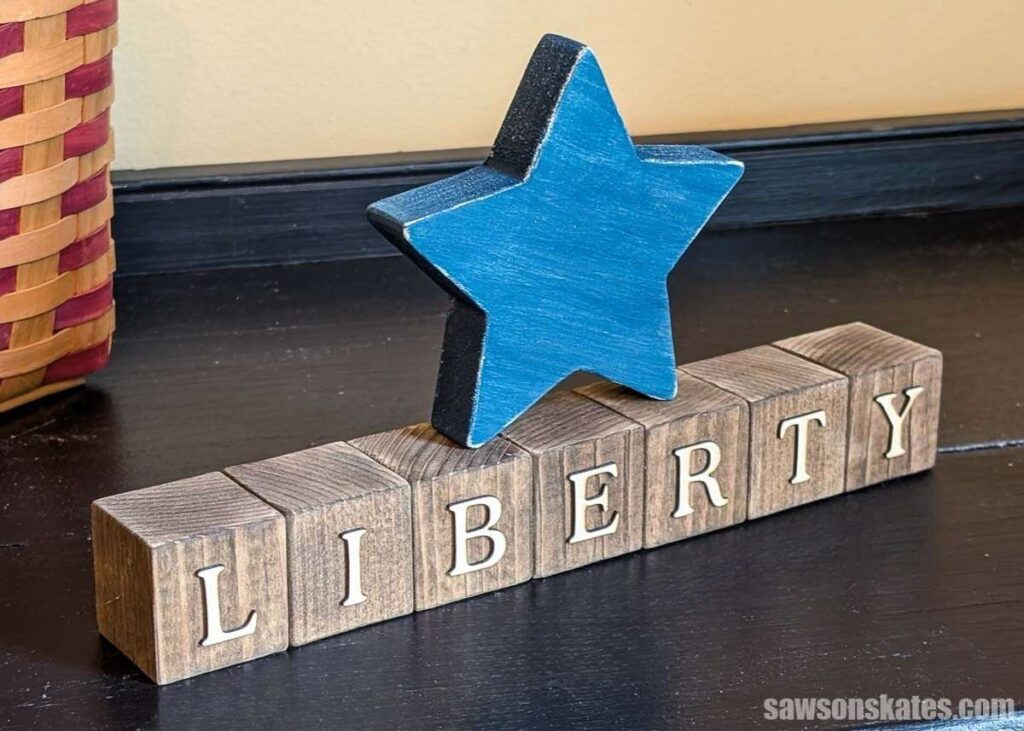 Wood block decoration featuring stained wood blocks that spell ‘LIBERTY’ and a blue wooden star.