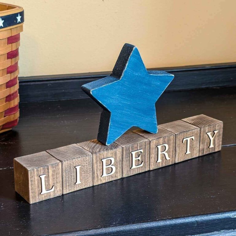 Wood block decoration featuring stained wood blocks that spell ‘LIBERTY’ and a blue wooden star.