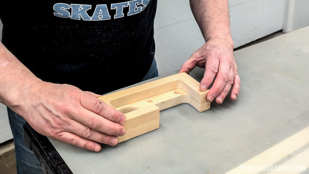 Hands aligning two U-shaped wooden pieces on a workbench after glue has been applied.
