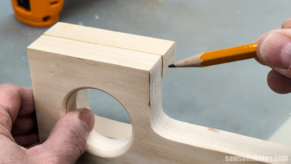 Pencil marking a slight misalignment at the phone slot on a glued wooden assembly.