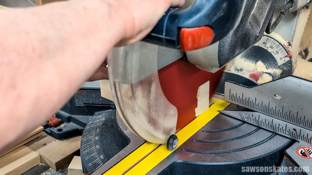 Miter saw cutting off a small wood piece.