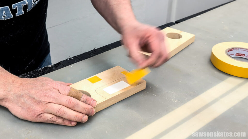 Hands applying double-side tape to a small wood block