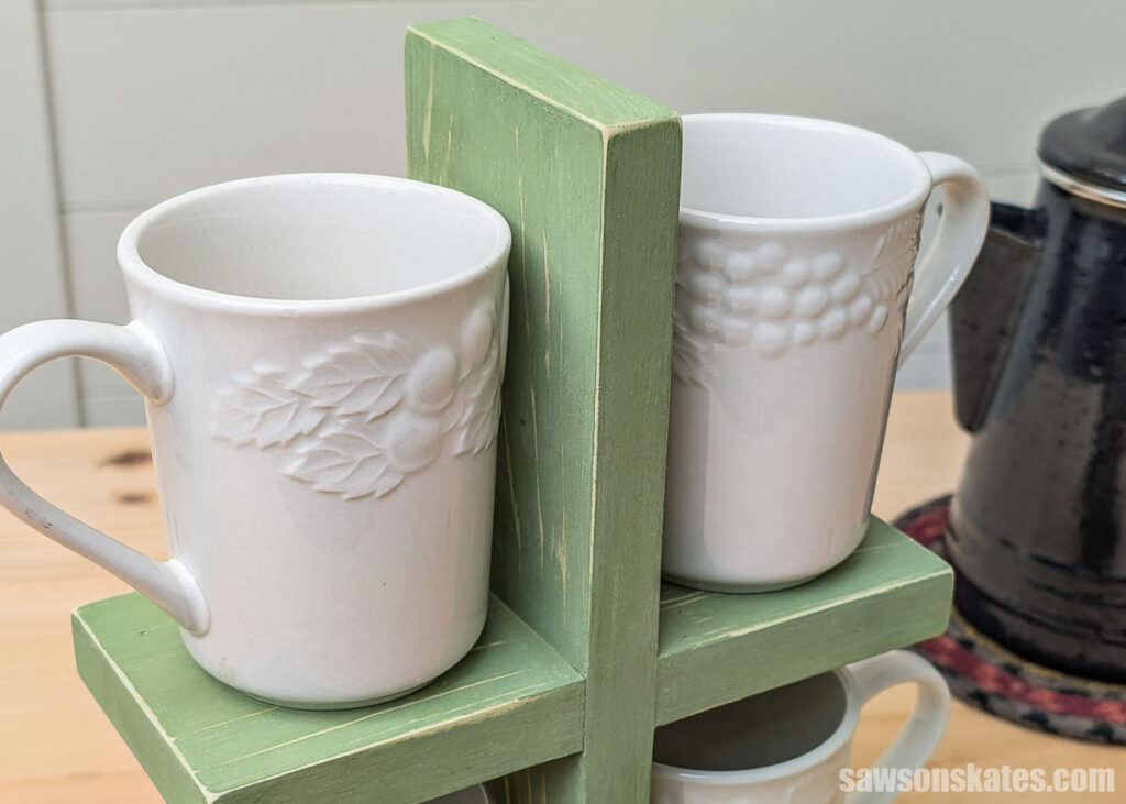 Closeup of a DIY stacked mug holder, painted green with two white coffee mugs