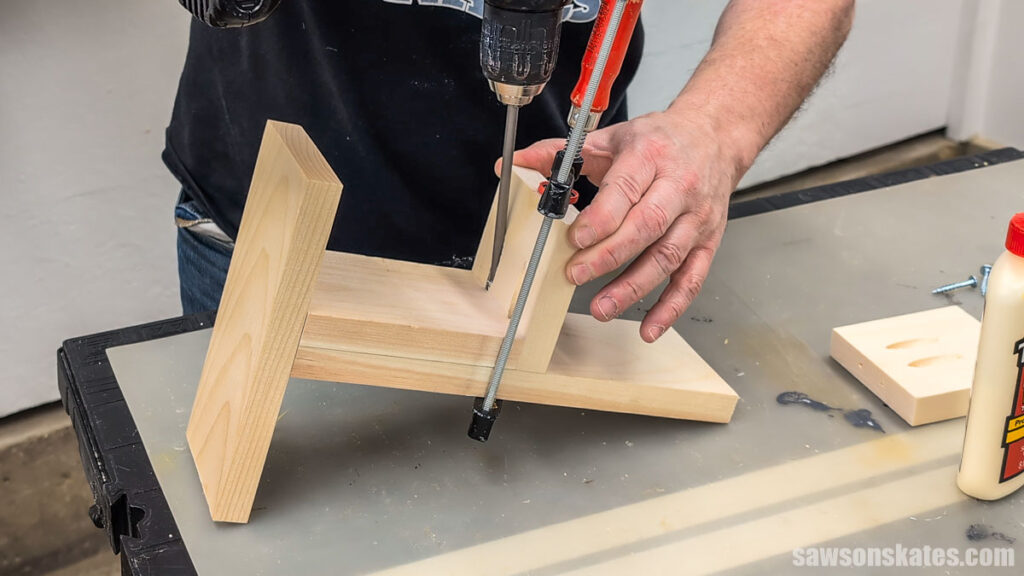 Using a drill to attach a shelf to the upright