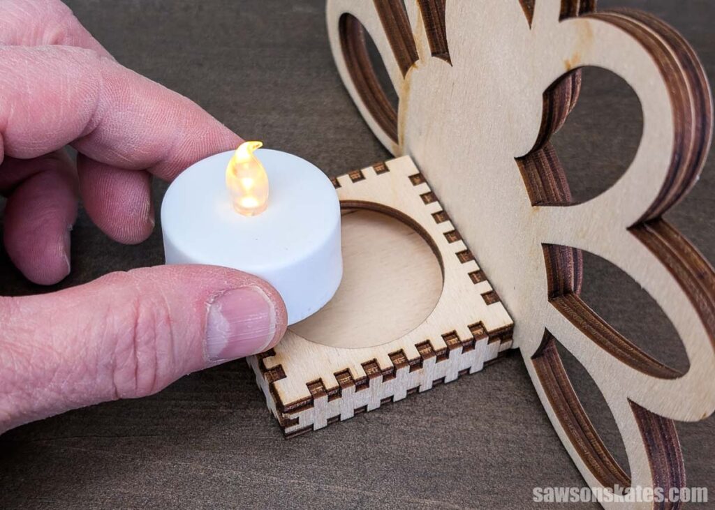 Hand placing an LED candle into a wooden thanksgiving tealight holder