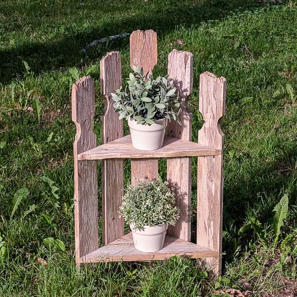 Two-shelf plant stand made from pickets in a grassy yard