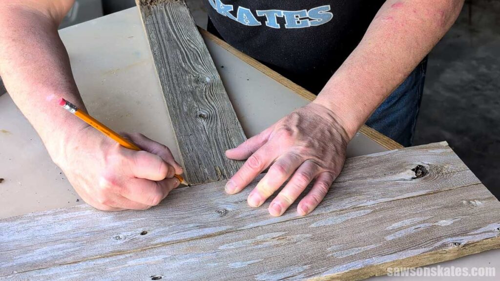 Person marking the edge of a board on a fence