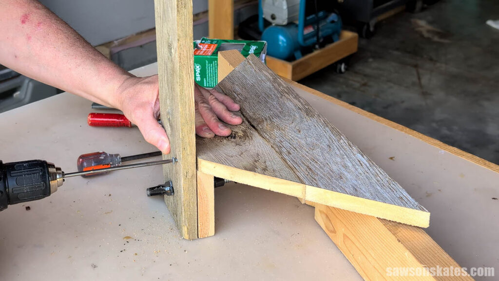 Driving a screw into the slat to attach it to the shelf