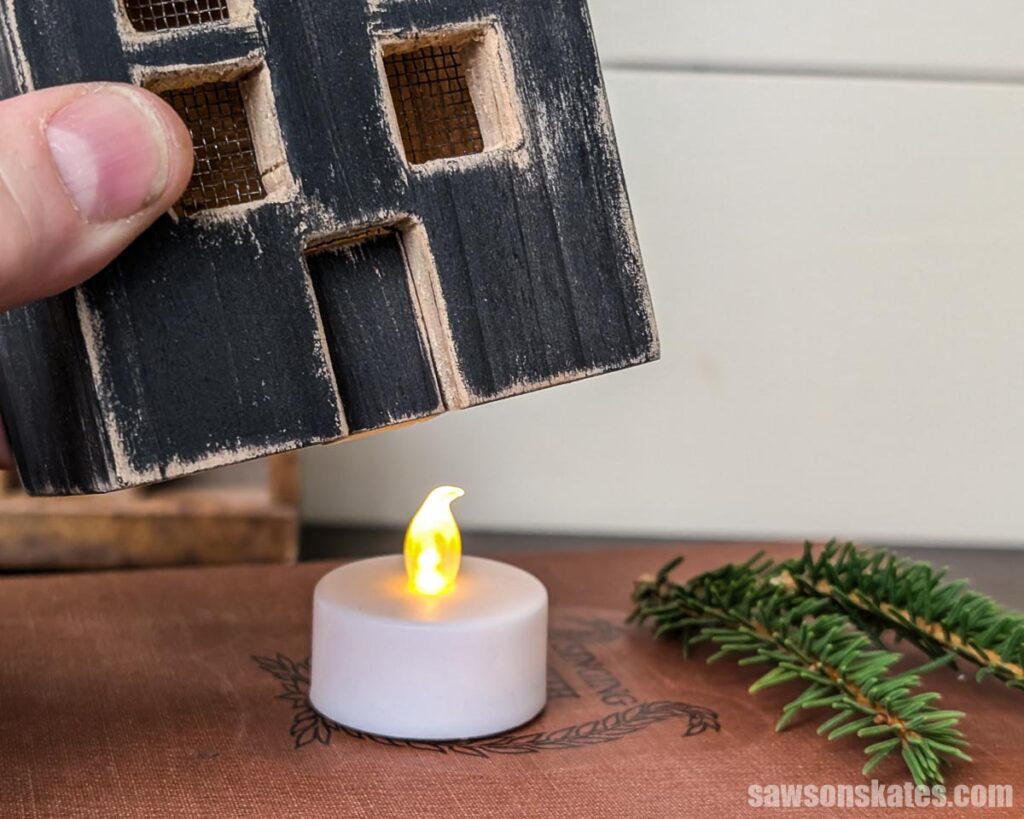Hand raising house luminary to show LED candle
