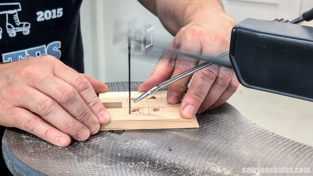 Using a scroll saw to cut out the windows in a house luminary