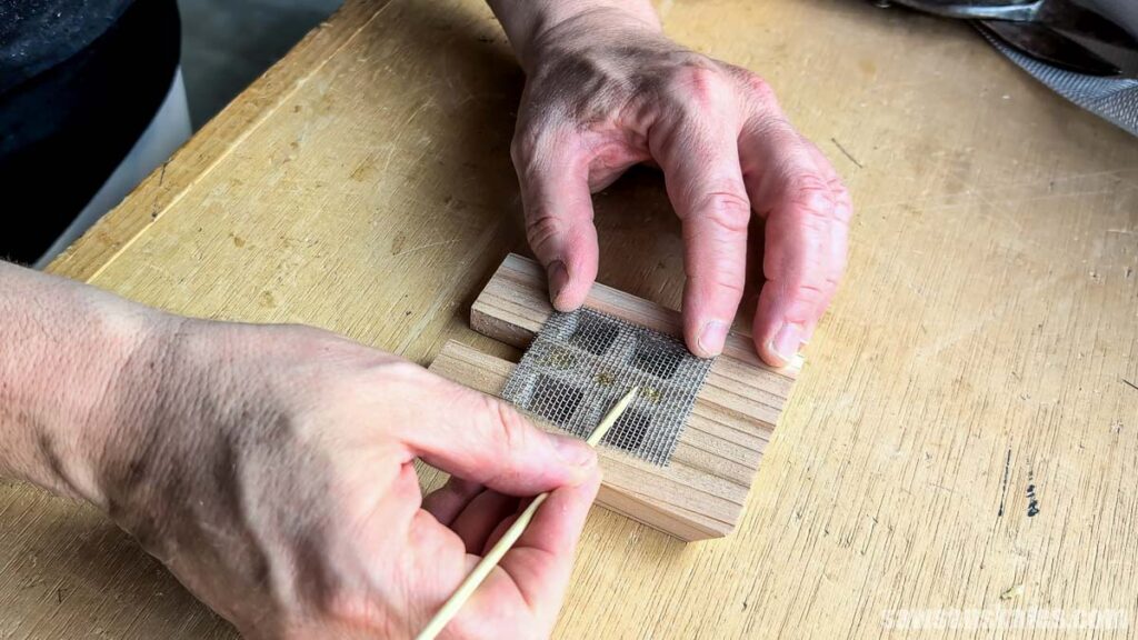 Using a wood skewer to press window screen mesh into place