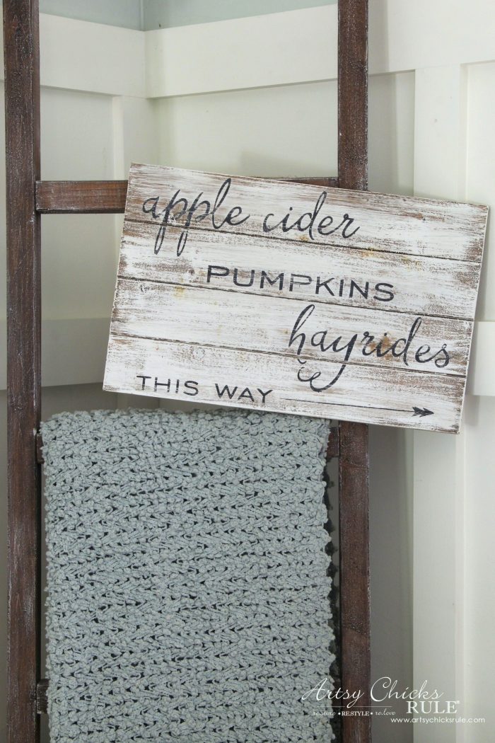 Wooden whitewash sign that says, apple cider, pumpkins, hayrides this way