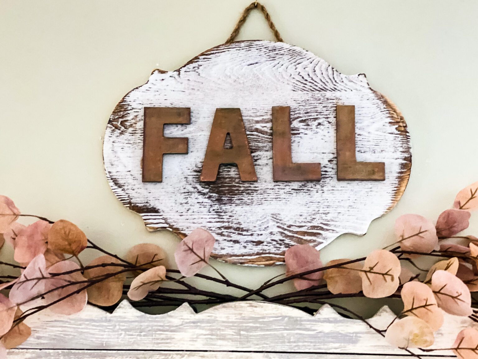 Wooden whitewashed sign with copper painted letters that say fall