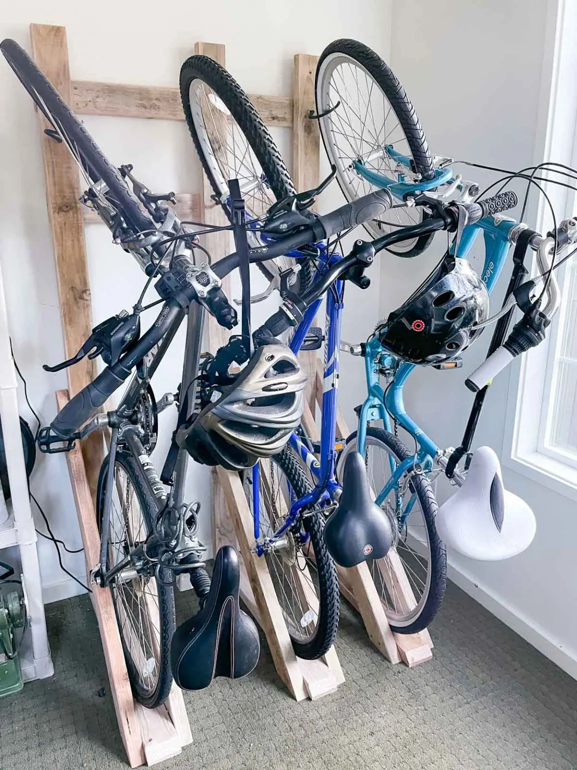 Wooden bike storage rack holding three bicycles and helmets.