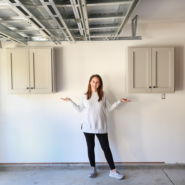 Person standing in an empty garage between two wall-mounted cabinets.