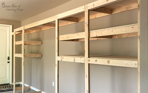 Wall-mounted wooden garage shelves with open storage space and a ladder-style side support.