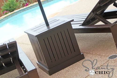 Dark brown patio side table with a slatted top and vertical slatted sides, featuring a center hole for a patio umbrella pole.