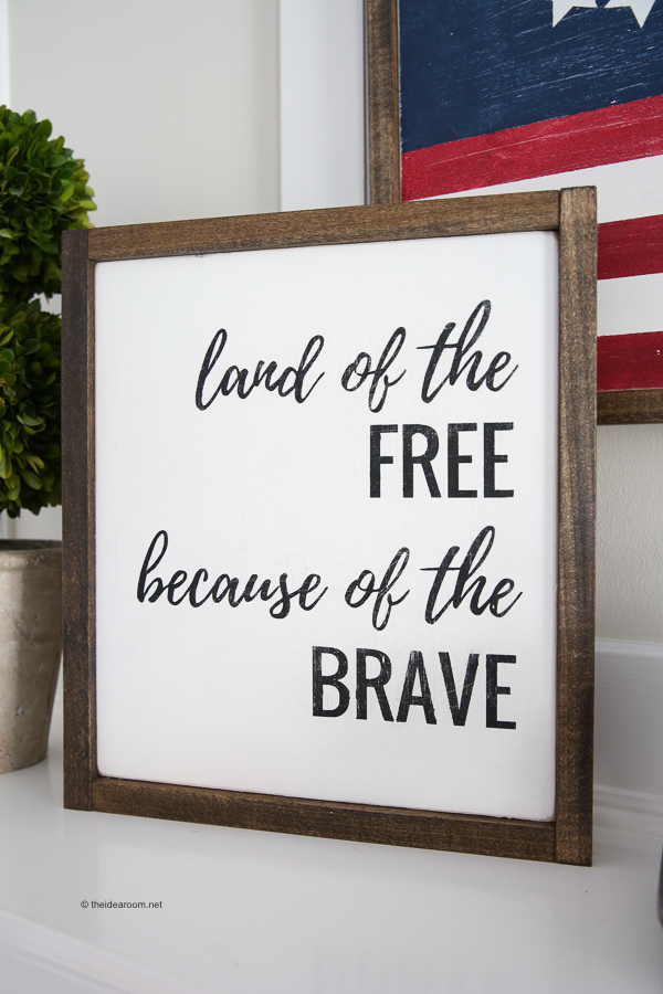 Framed patriotic quote sign with black lettering on a white background that reads, "land of the FREE because of the BRAVE."