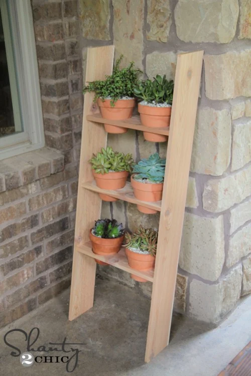 Wooden plant stand leaning against a brick wall with six terracotta pots