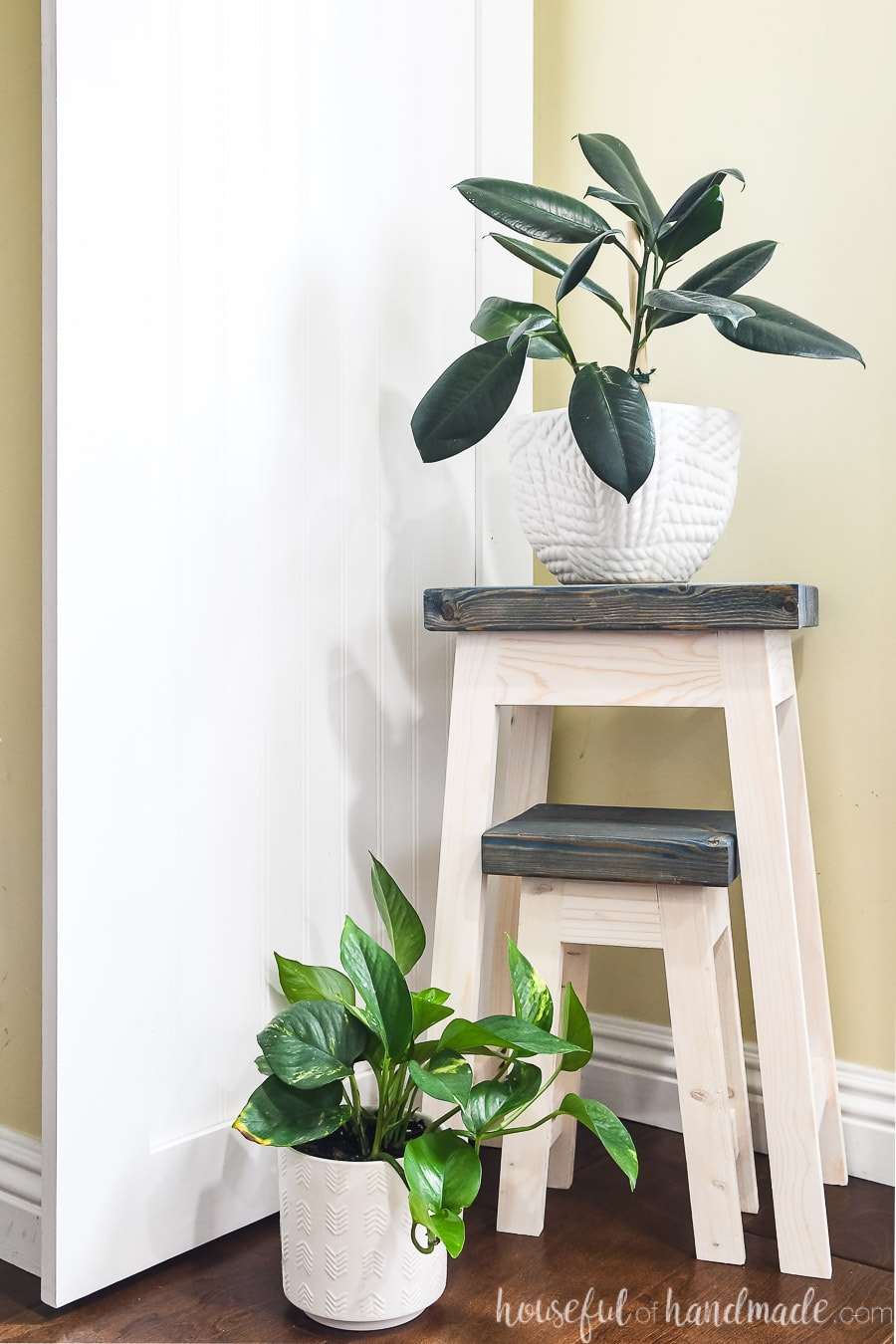 Nesting plant stands painted white with dark tops next to a wall