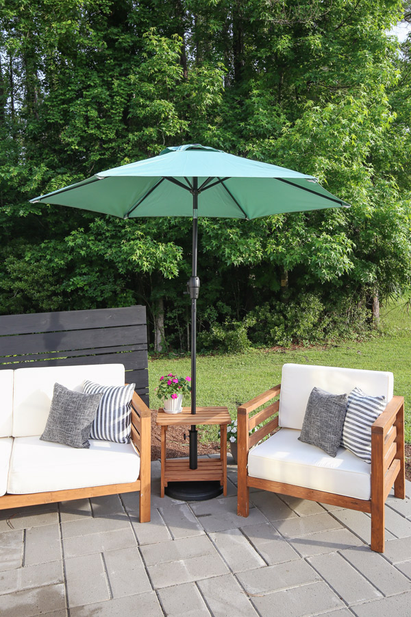 Wood umbrella stand with a outdoor sofa and chair on either side
