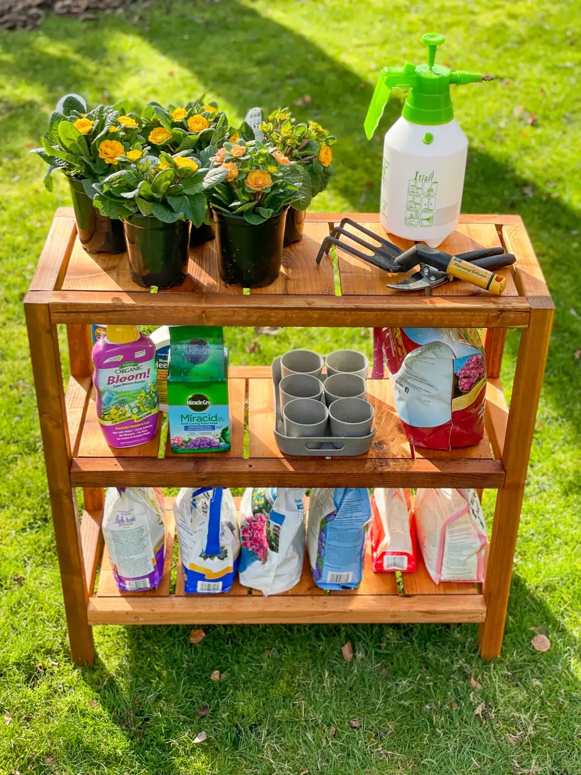 Wood shelves filled with plants and garden supplies on a grassy lawn