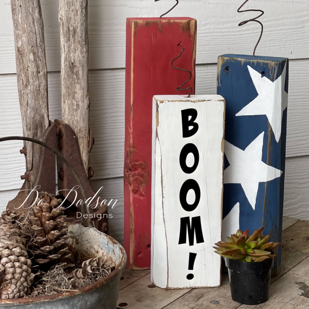 Patriotic wooden porch decor featuring three distressed wood blocks painted to look like firecrackers.