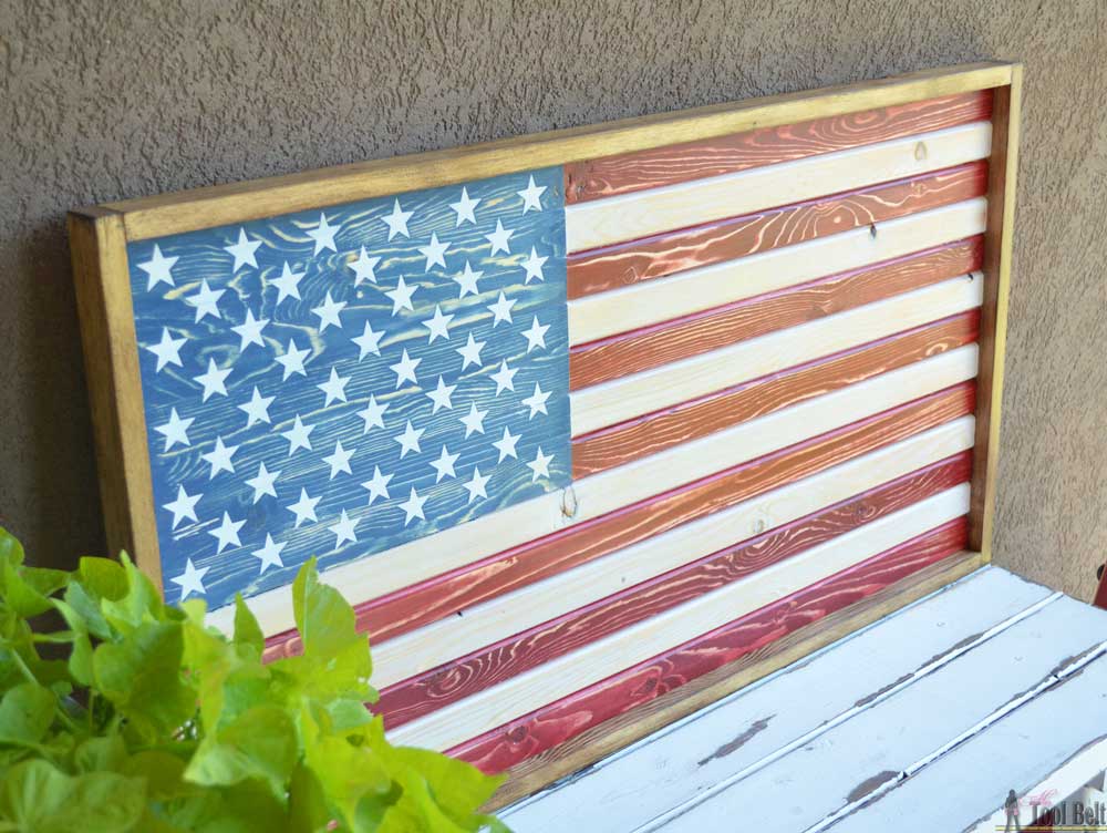 Framed wooden American flag wall art featuring a blue field with white stars and alternating red and natural wood stripes.