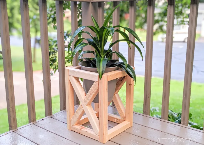 Wooden plant stand with an X brace on a deck