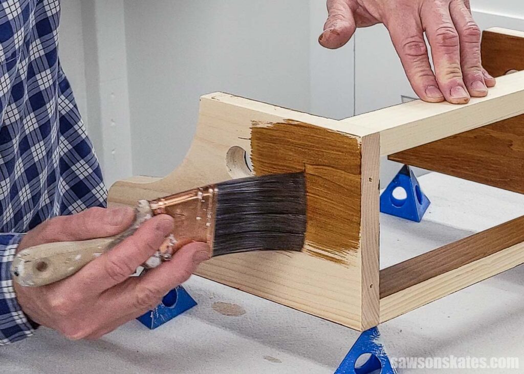 Hand applying wood stain on pine with a brush