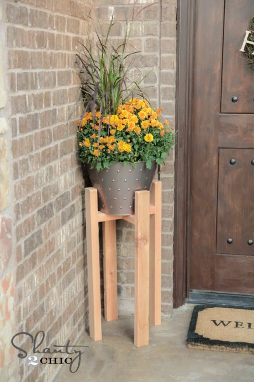 Tall plant stand with a potted mum next to a front door