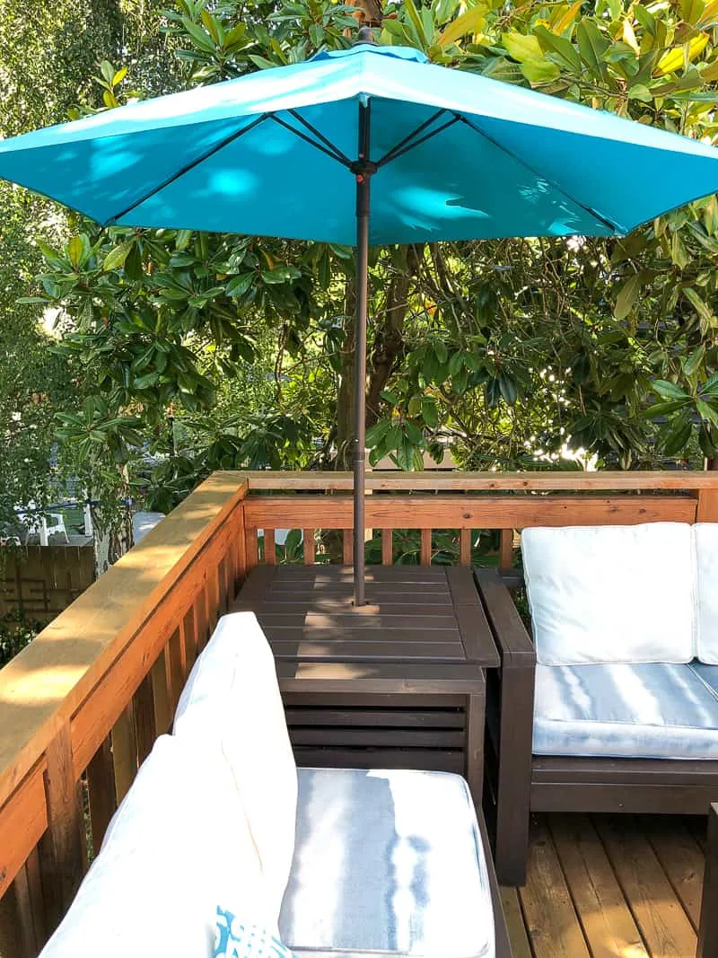 A patio umbrella stand between a sectional sofa.